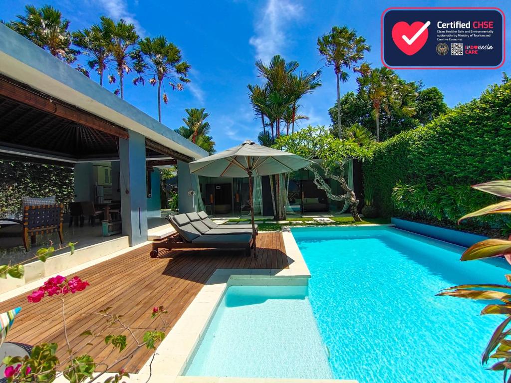 a swimming pool with an umbrella next to a house at Kembali Villas in Seminyak