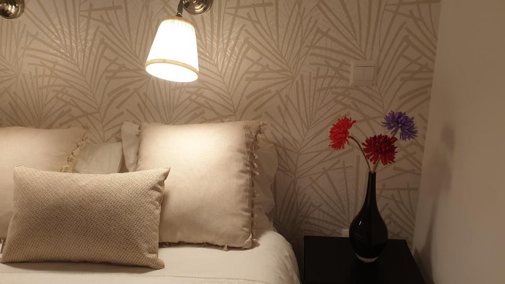 a vase with flowers on a table next to a bed at Azabache in Toledo