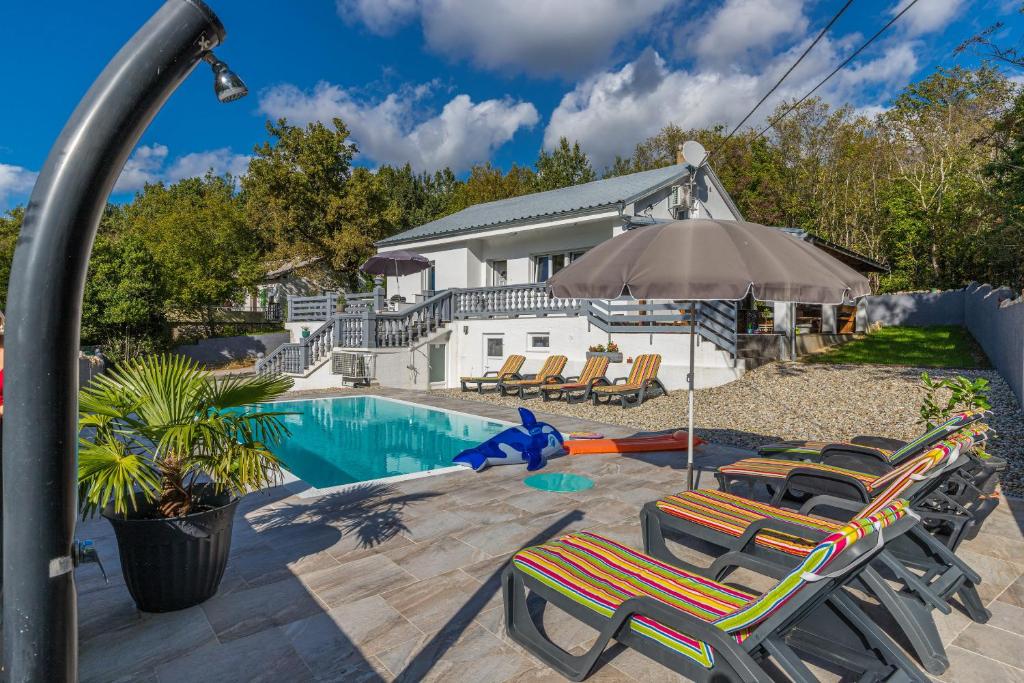 a pool with chairs and an umbrella next to a house at Villa Manta Crikvenica in Crikvenica