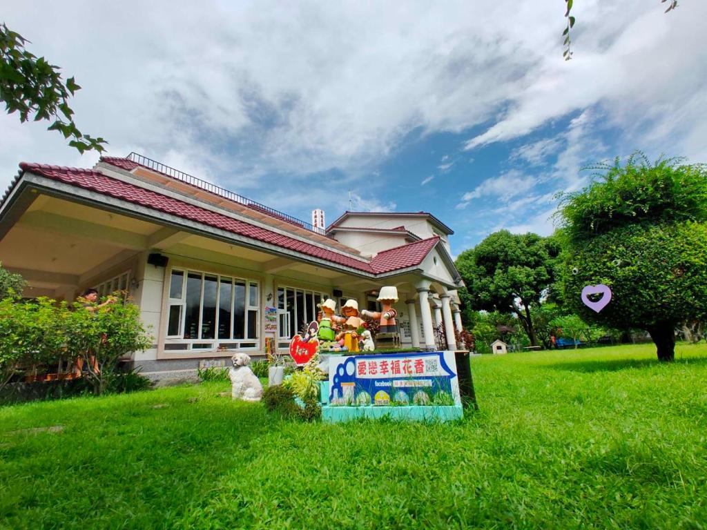 una pequeña casa con un cartel en el césped en 屏東幸福莊園庭園民宿, en Gaoshu