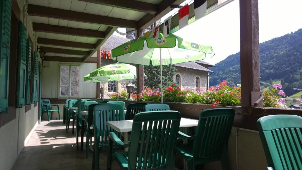 ein Restaurant mit grünen Stühlen, Tischen und einem Sonnenschirm in der Unterkunft Helvetia in Troistorrents