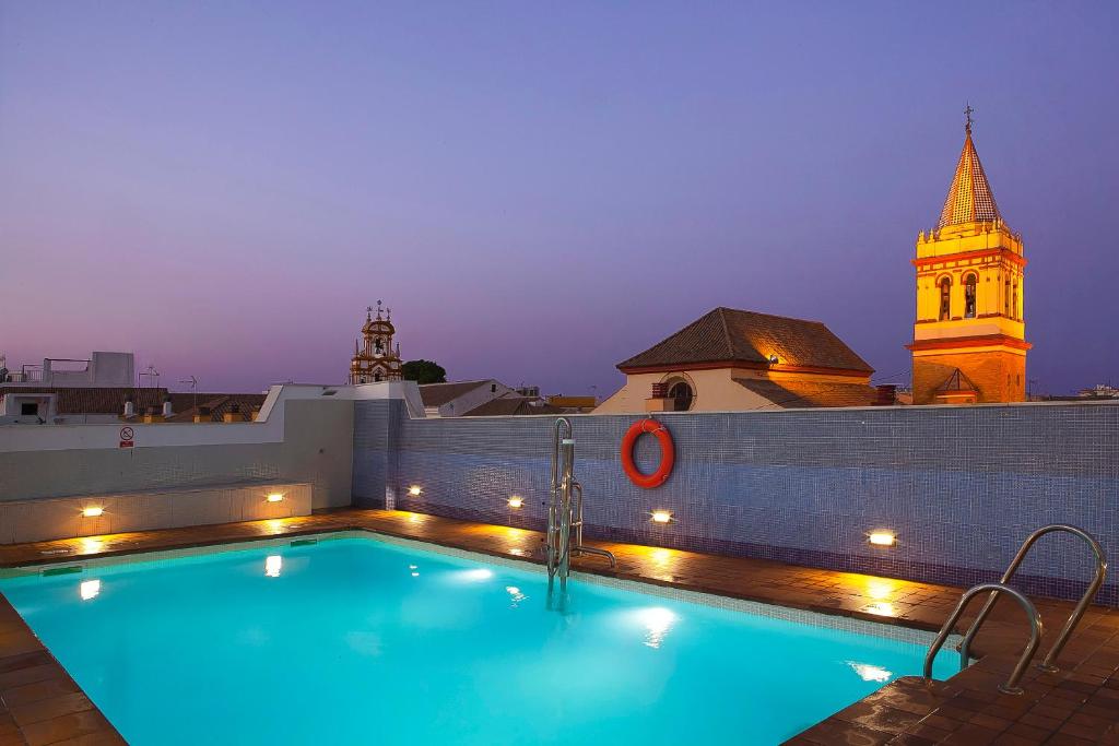 una piscina en la azotea de un edificio con una torre de reloj en San Gil, en Sevilla