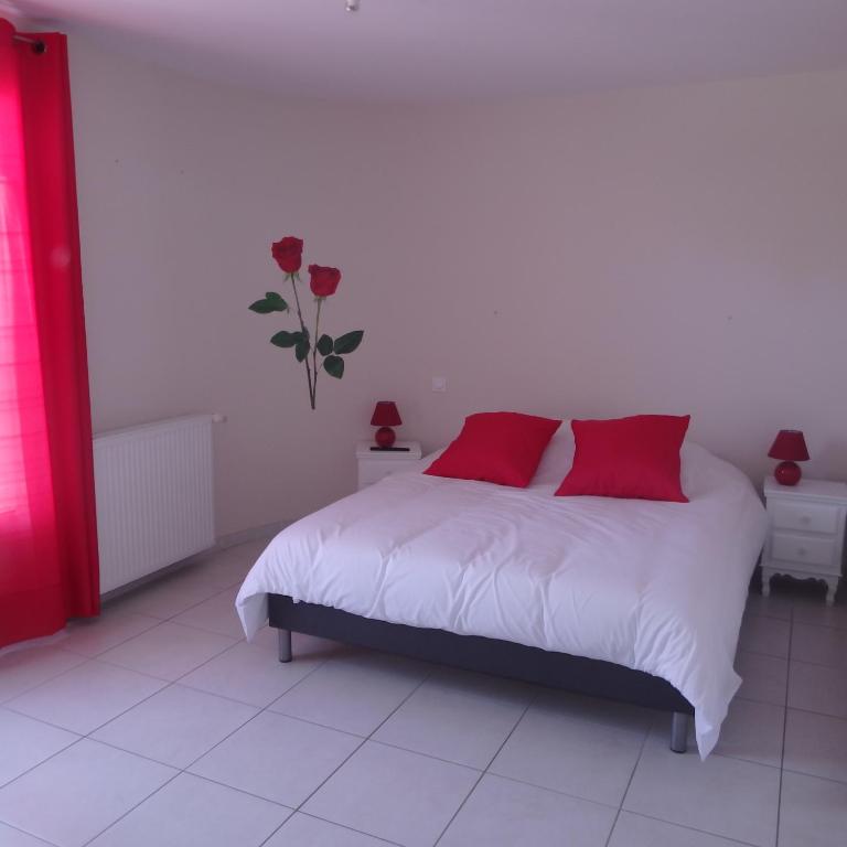 a bedroom with a white bed with red pillows at L&#39;oustal des Fontanilles in Castelnaudary