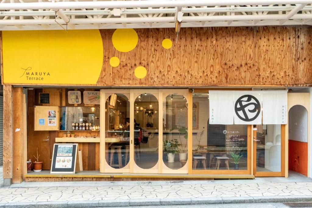 una tienda frente a un restaurante con una pared amarilla en Guest House MARUYA en Atami