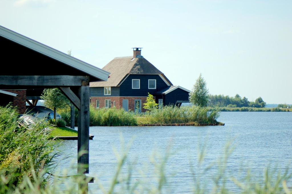 a house sitting on the edge of a body of water at Waterresort Bodelaeke Giethoorn in Giethoorn