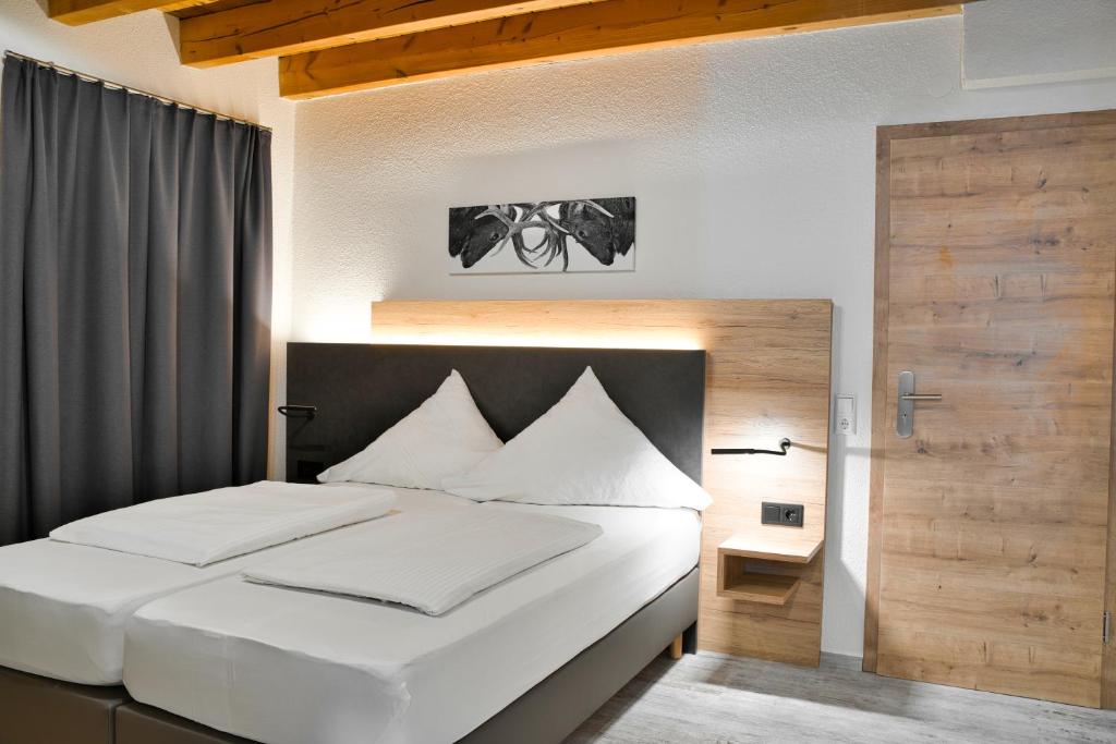Schlafzimmer mit einem großen weißen Bett mit einem Kopfteil aus Holz in der Unterkunft Landgasthof Hirschen GbR in Hohentengen
