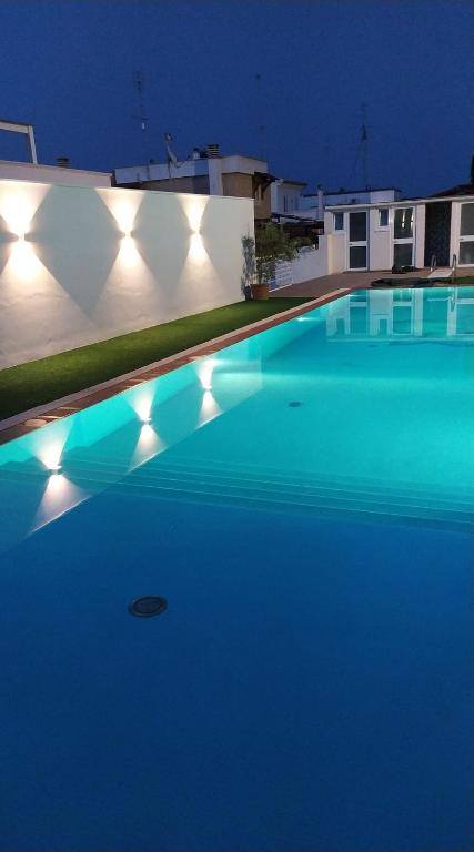 a large swimming pool with blue water at night at PURA B&b in Noicattaro