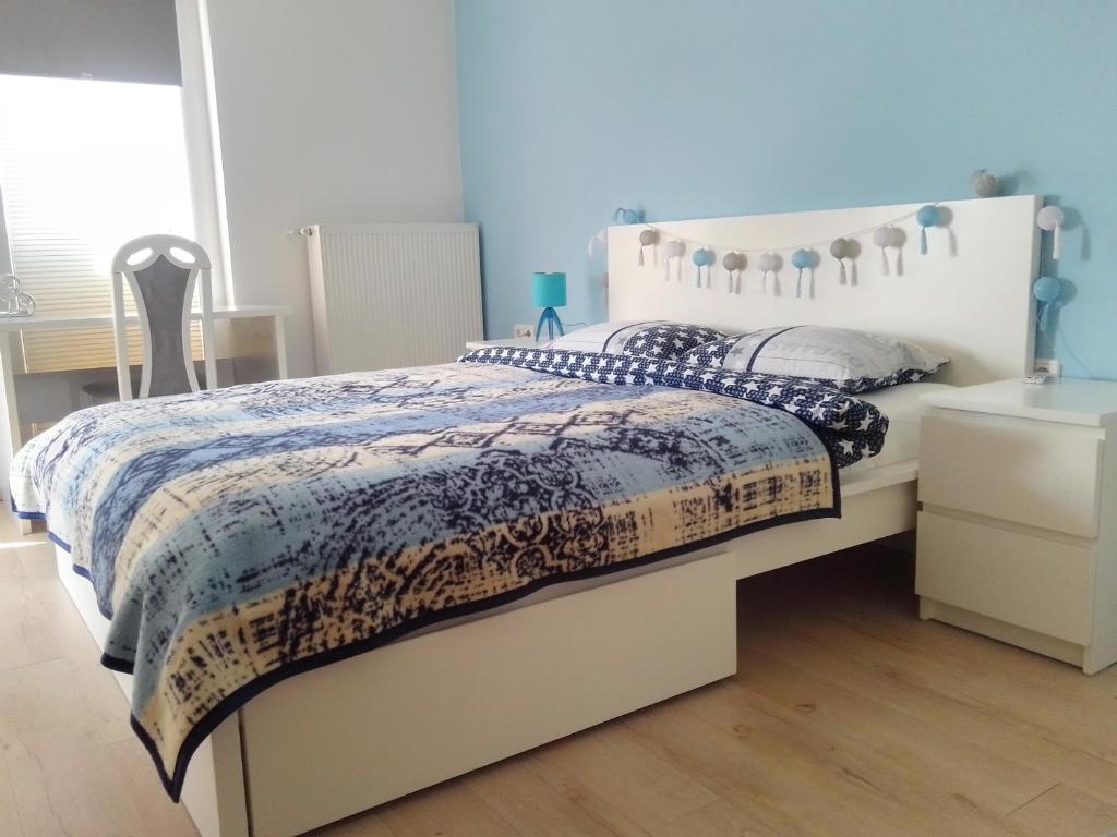 a bedroom with a white bed with a blue comforter at Apartman Botivo in Ludbreg