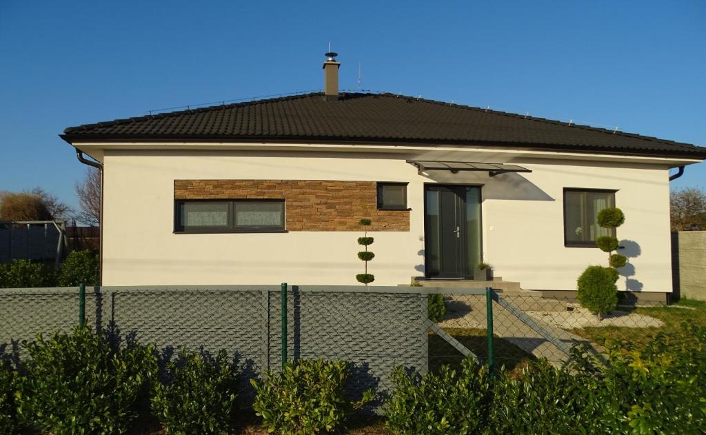 uma casa branca com uma cerca à frente. em Jenny home em Mojmírovce