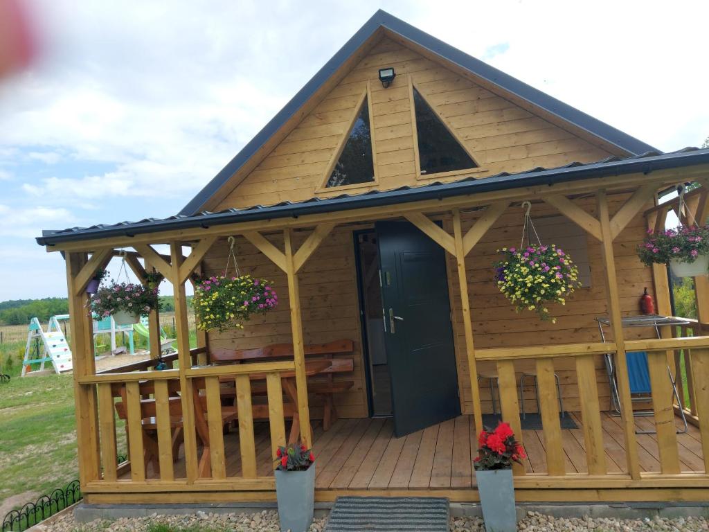 a large wooden cabin with a porch and a blue door at Na polance dwa domki in Chłopy