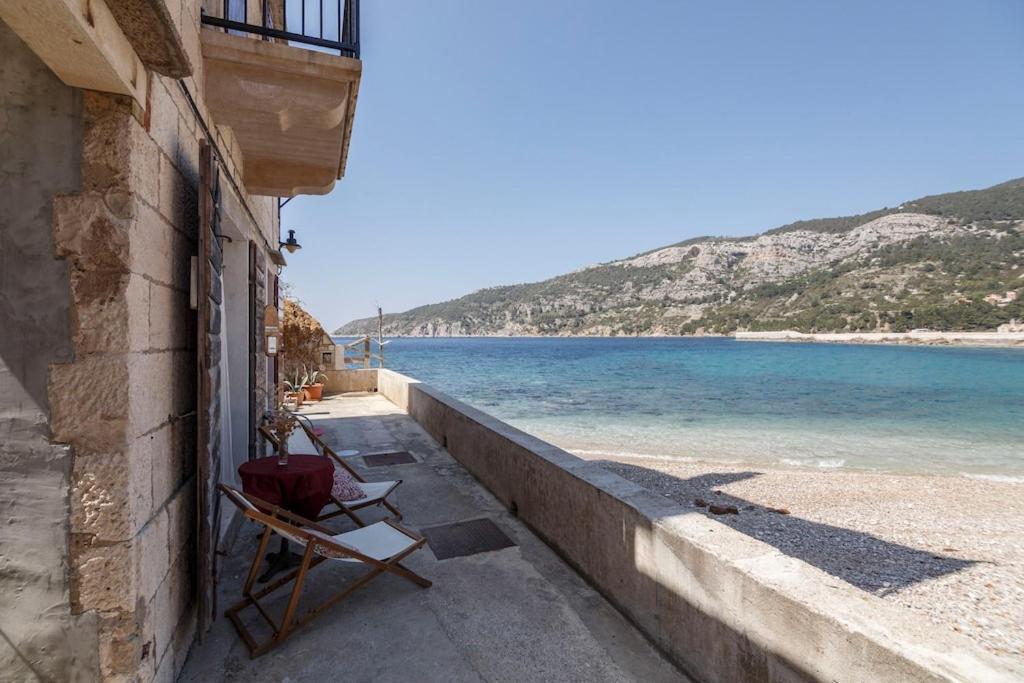 a chair sitting on a wall next to a beach at Beachfront Love Nest in Komiža