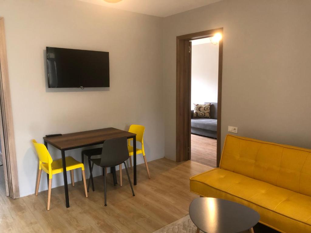 sala de estar con mesa, sillas amarillas y sofá en Bubu's Home, en Batumi