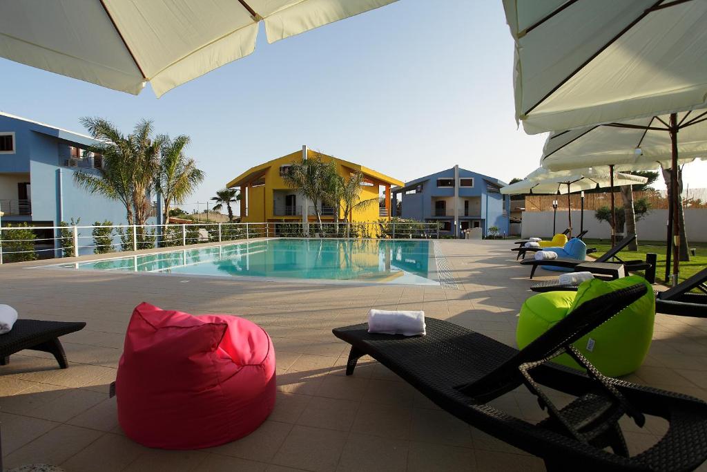 a swimming pool with chaise lounges and chairs next to a resort at BfB Residence San Marco in Sciacca