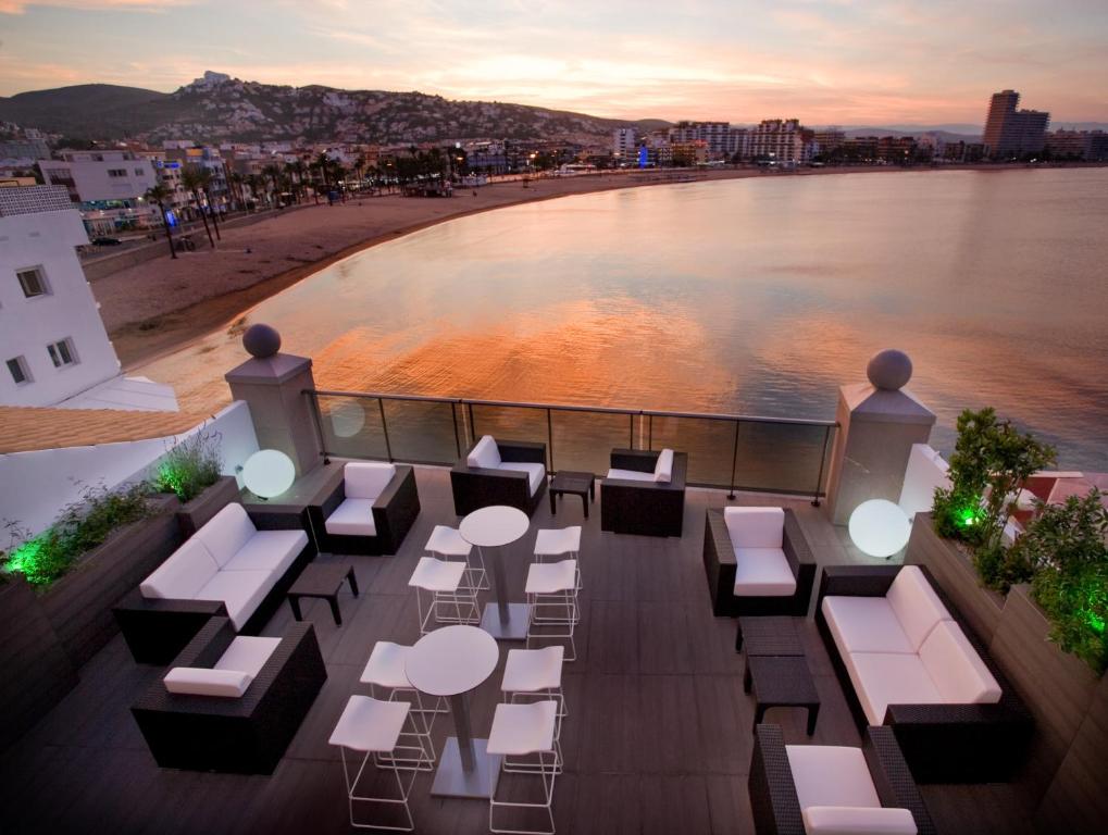 a balcony with tables and chairs and a view of the water at Hotel Boutique La Mar - Adults Only in Peniscola