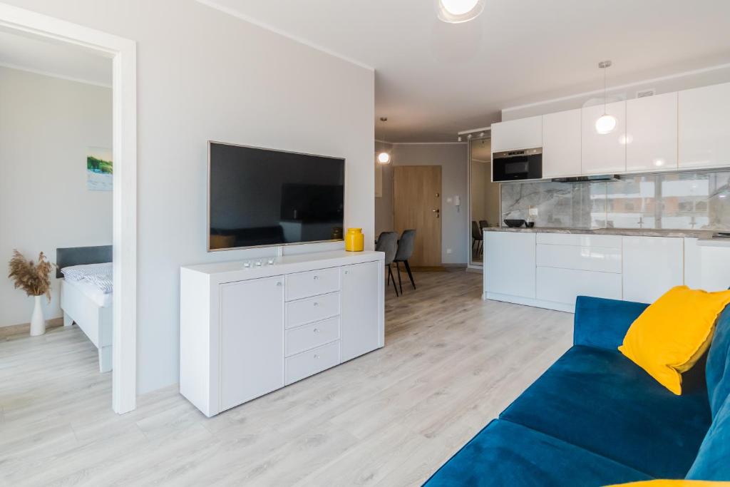 een woonkamer met een blauwe bank en een keuken bij Apartament Baltic Sun N°36 in Sztutowo