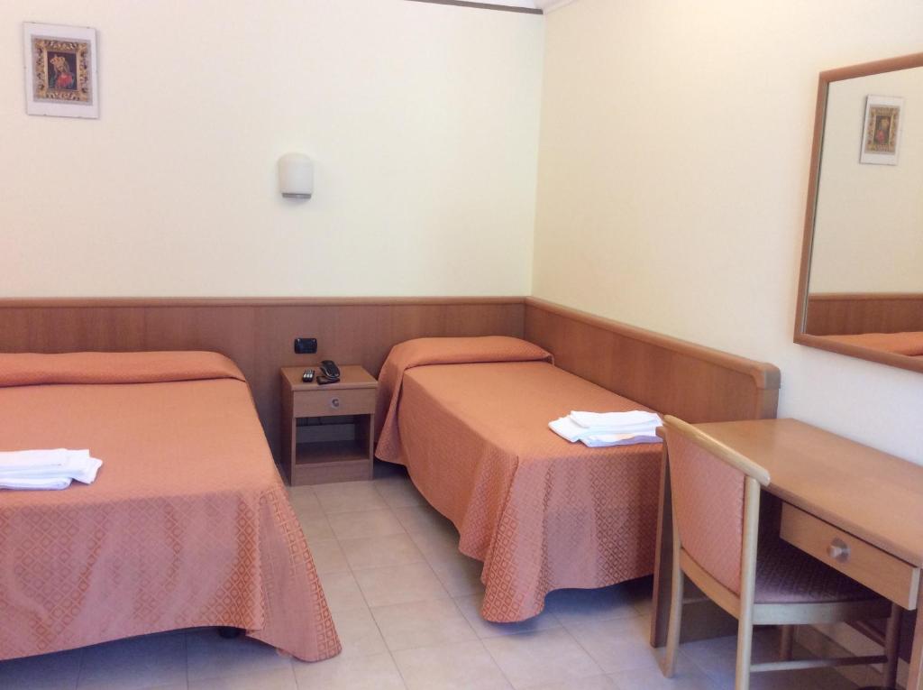 a room with two beds and a table and a mirror at Hotel Il Saraceno in Volastra