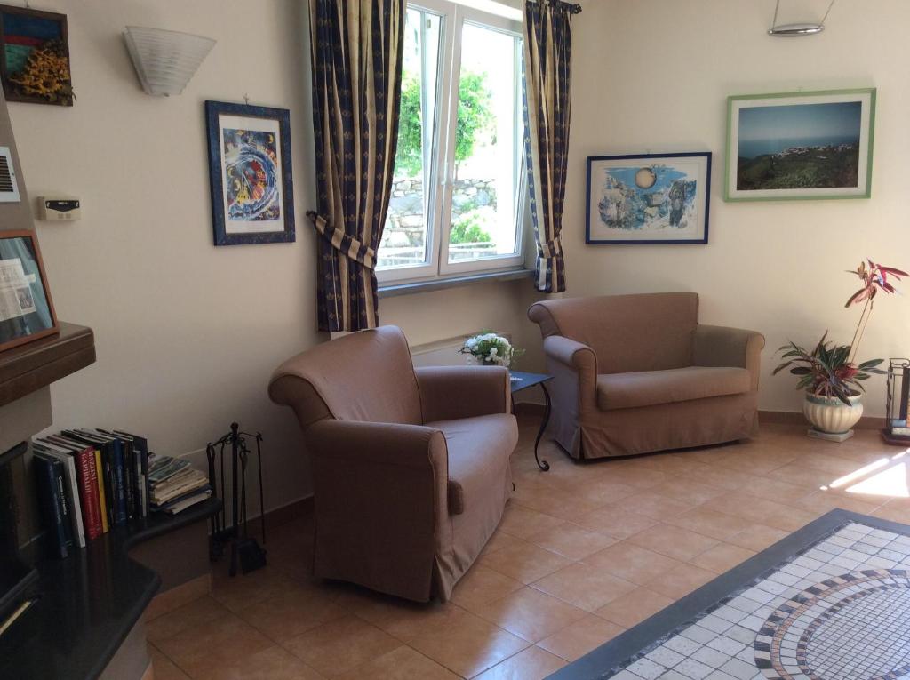 a living room with two chairs and a window at Hotel Il Saraceno in Volastra