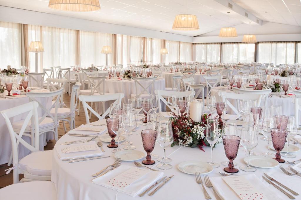 a banquet hall with white tables and white chairs at La Costa Hotel Golf & Beach Resort in Pals