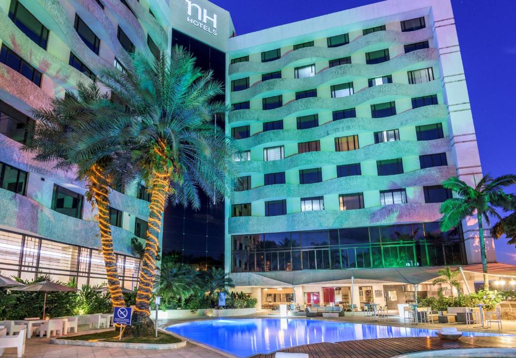 卡利的住宿－卡利皇家NH酒店，一座建筑前有棕榈树的酒店