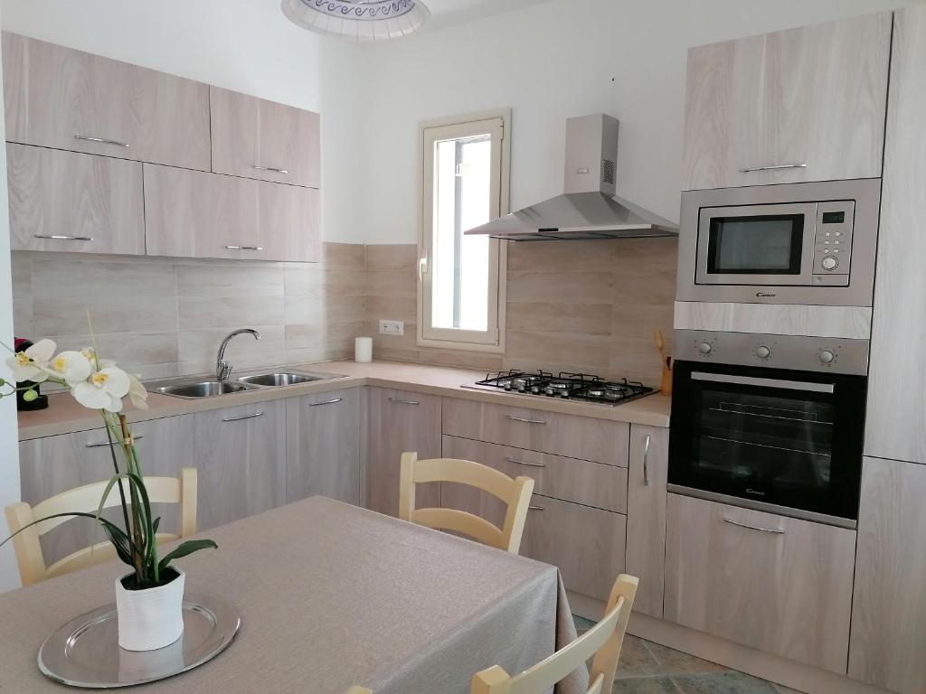 a kitchen with a table with a vase of flowers at Marea Apartment in Tanaunella