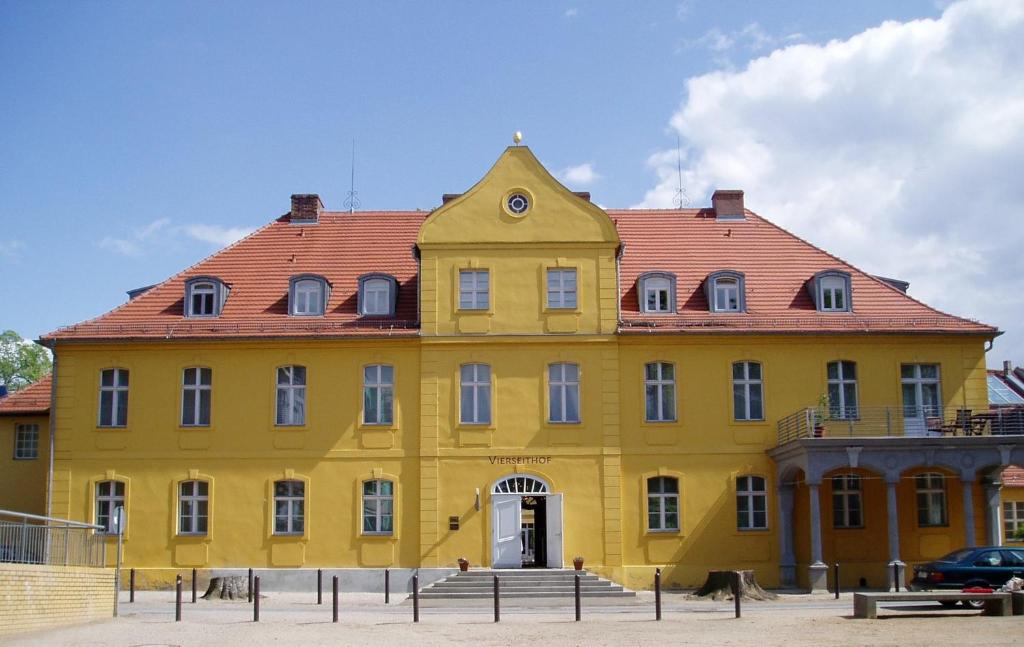 Hotel Vierseithof Luckenwalde في لوكنفالده: مبنى اصفر كبير بسقف احمر