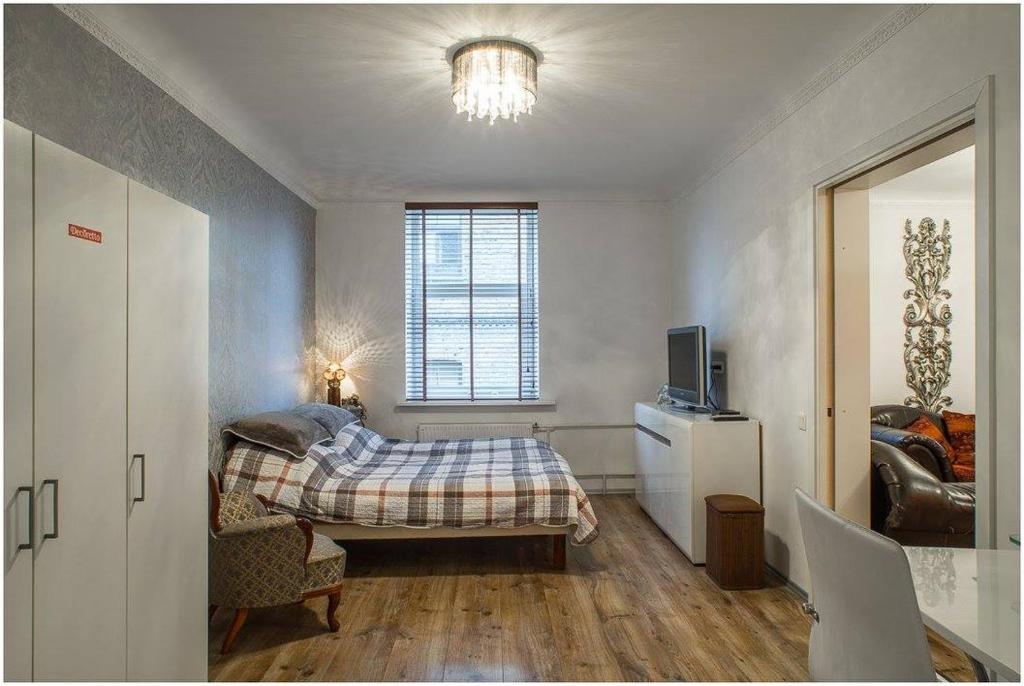 a bedroom with a bed and a tv and a window at Cerntal Luxury Apartment in Rīga