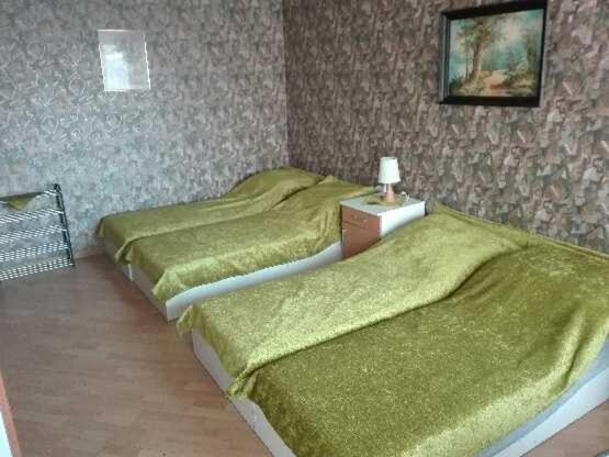 a bedroom with two beds with green sheets and a table at Suwałki Centrum in Suwałki