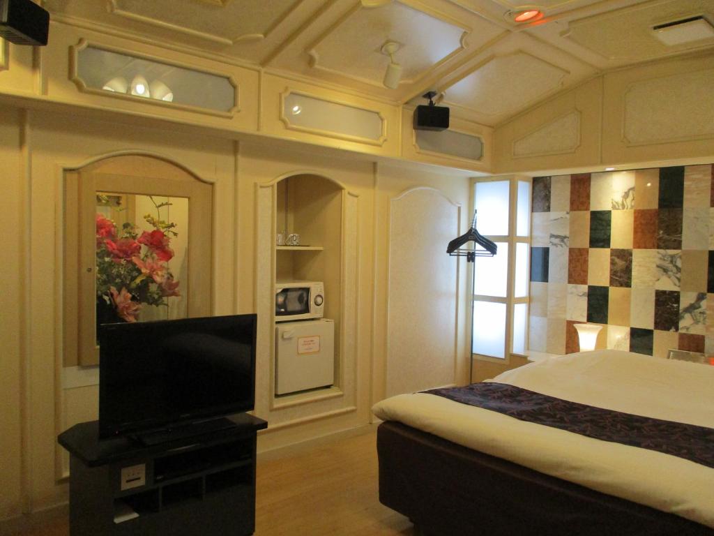 a bedroom with a bed and a flat screen tv at ホテルハンズ in Ginan