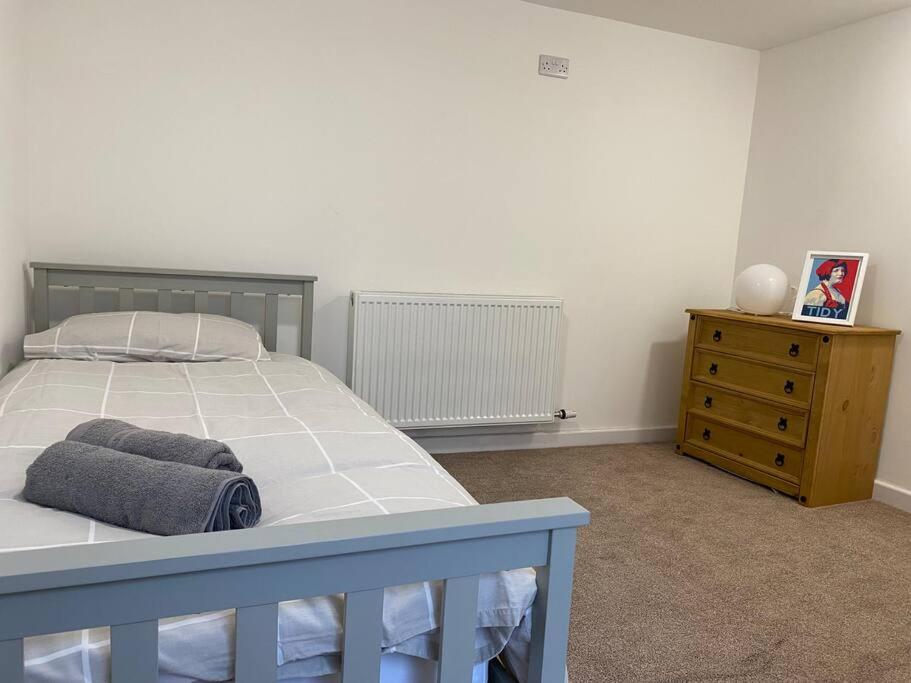 a bedroom with a bed and a wooden dresser at Modern 2 bedroom cottage near Bike Park Wales. in Merthyr Tydfil