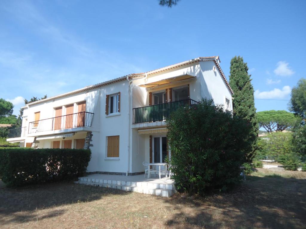 een wit huis met een balkon en een tuin bij Les Lucioles in Cavalaire-sur-Mer