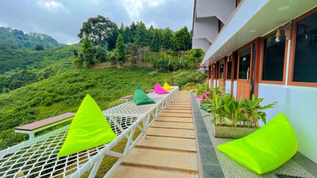 a balcony with green and pink chairs and a mountain at De Pointé Resort & Resto in Campaka