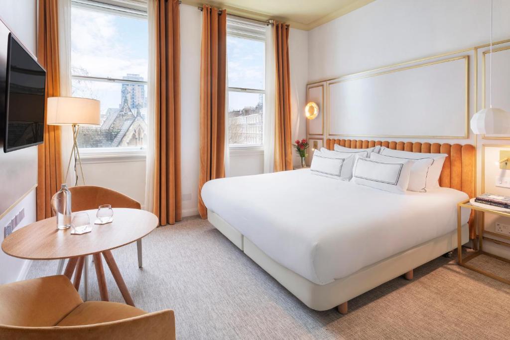 una habitación de hotel con una gran cama blanca y una mesa en Meliá London Kensington Member of Meliá Collection, en Londres
