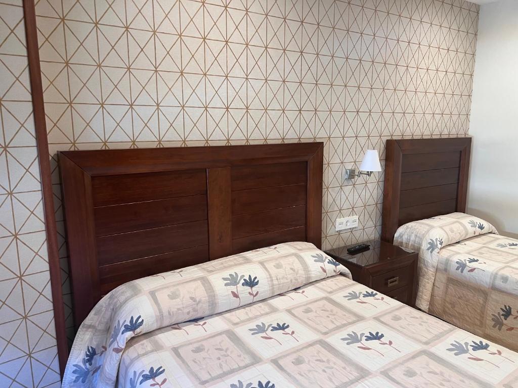 a bedroom with two beds and a tiled wall at Hostal Avenida in Benavente