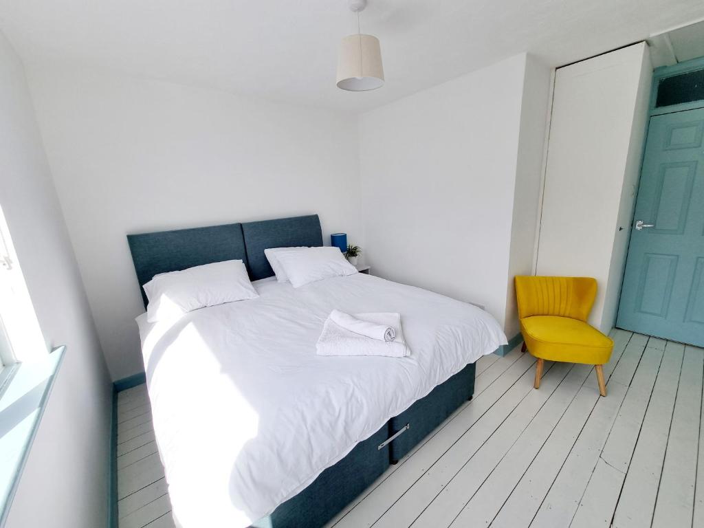 a bedroom with a bed and a yellow chair at Visit Seaford Apartment - 4 Bedrooms in Seaford