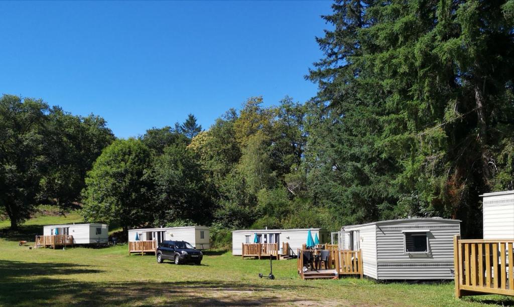 un groupe de mobile homes et une voiture garée dans un champ dans l'établissement Camping Les Roussilles, à Saint-Sylvestre