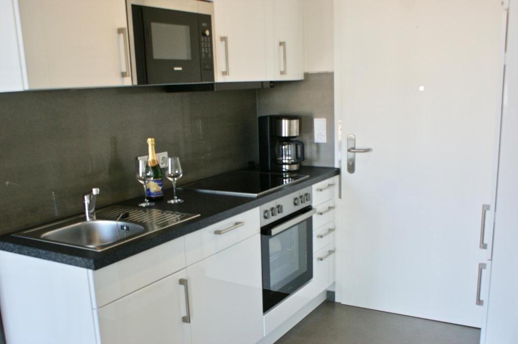 a kitchen with white cabinets and a sink and a refrigerator at Fehmarn-OstseeferienStrandresidenz Vogelflug 14312 in Fehmarnsund