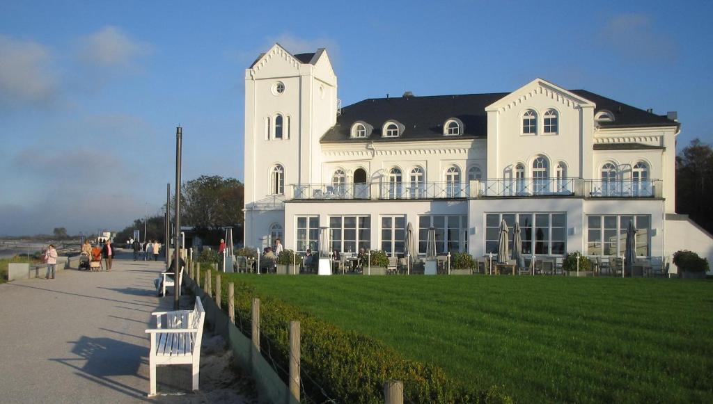 ein großes weißes Gebäude mit einem Rasen davor in der Unterkunft Haus Bischofsstab - Ferienwohnung am Meer in Heiligendamm