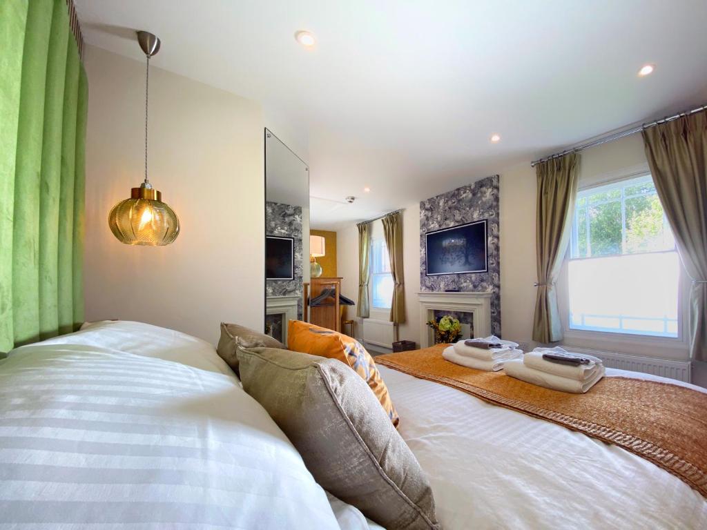 Schlafzimmer mit einem großen weißen Bett und grünen Vorhängen in der Unterkunft Hambrook House Canterbury - NEW luxury guest house with ESPA Spa complex in Canterbury