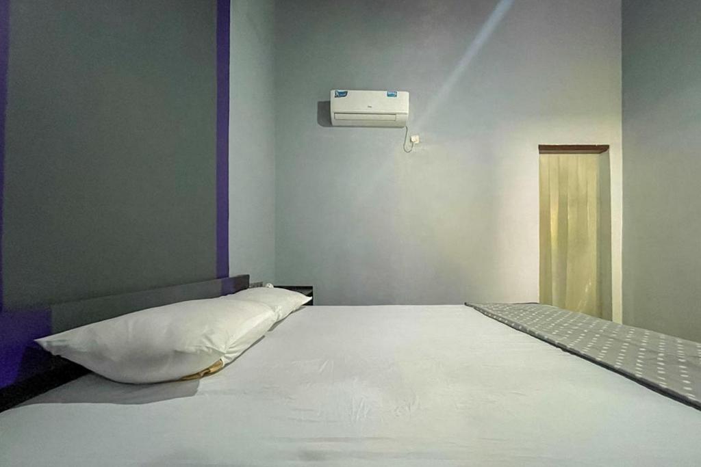 Un dormitorio con una gran cama blanca en una habitación. en Mbah Mek Trawangan Homestay, en Gili Trawangan