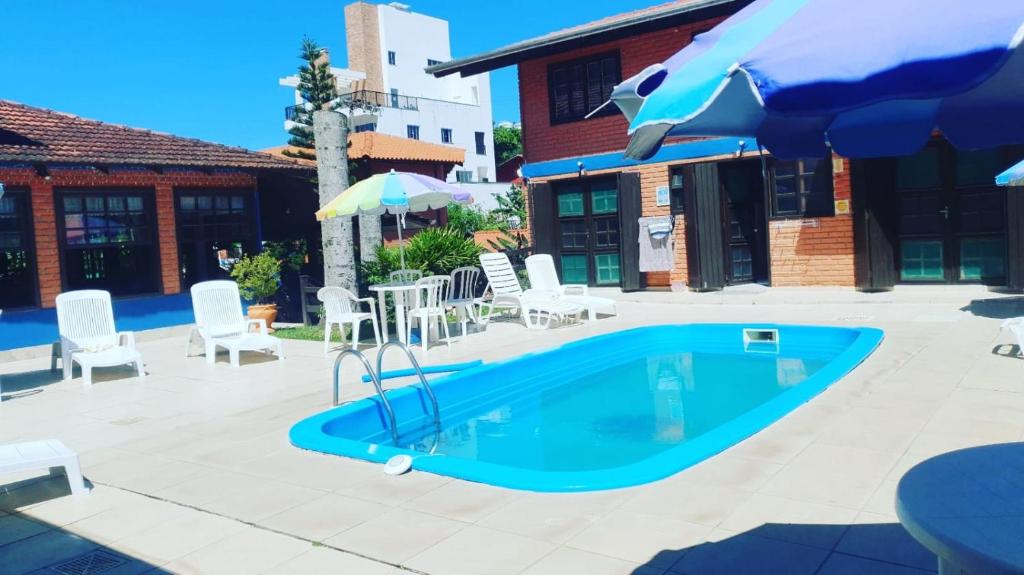 a swimming pool with chairs and an umbrella at Sunshine Residencial in Bombinhas
