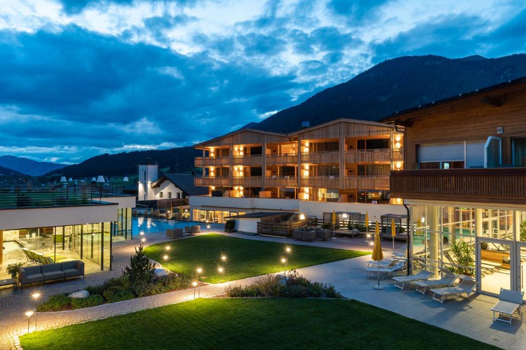 a view of a hotel at night with a lawn at Alpine Nature Hotel Stoll in Valle Di Casies