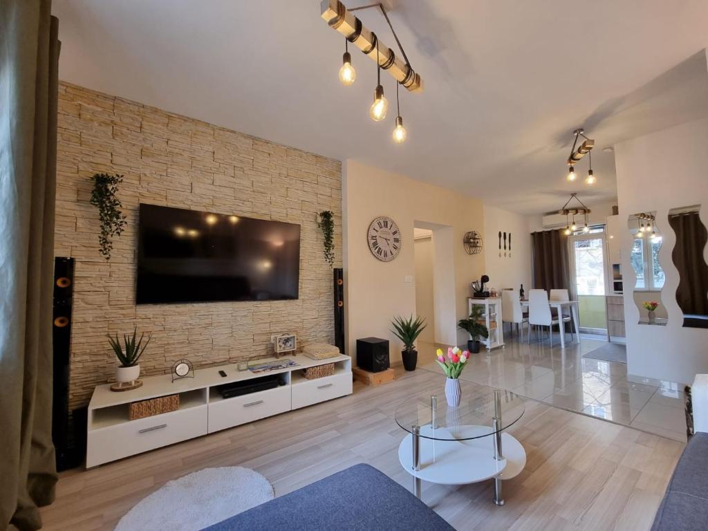 - un salon avec une grande télévision sur un mur en briques dans l'établissement Apartment Lux Zadar, à Zadar