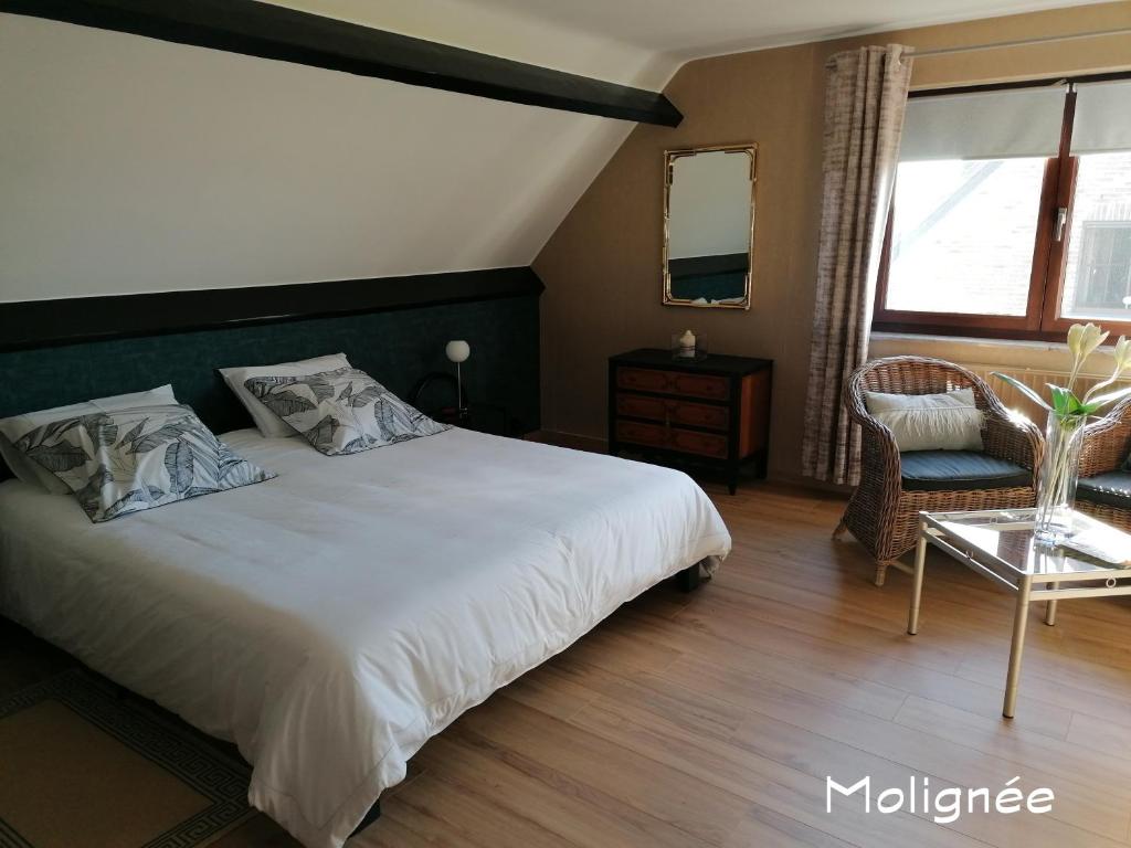 a bedroom with a large white bed and a chair at Le Cerisier in Bioul