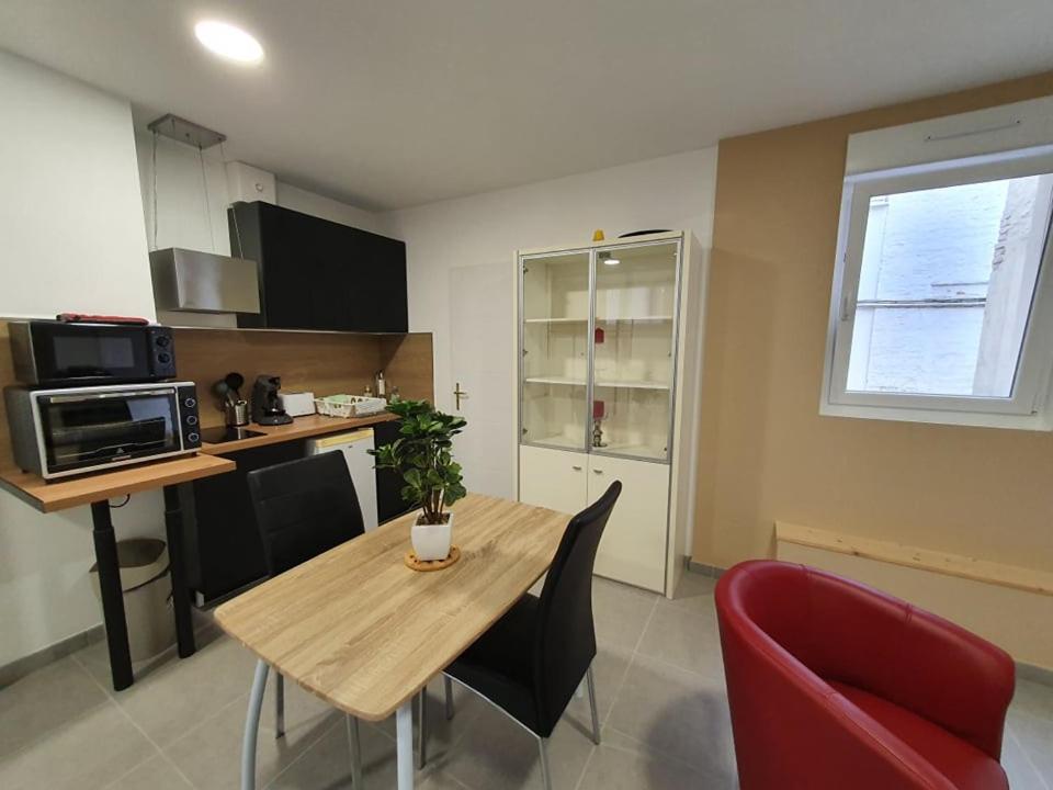 eine Küche mit einem Holztisch und einem roten Stuhl in der Unterkunft Grand studio Gravelines centre , 5 mn du cnpe et de la plage, absence de chambre privative in Gravelines