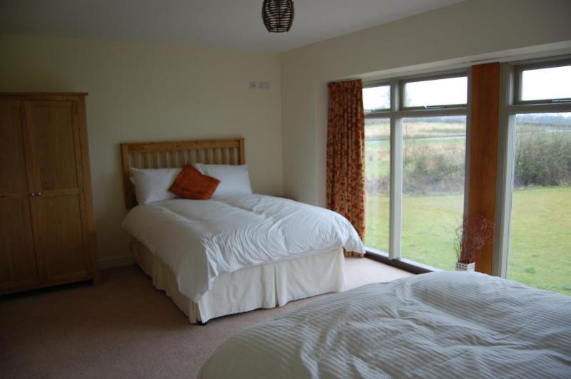 a bedroom with two beds and a large window at Canons Court Mews in Wotton under Edge