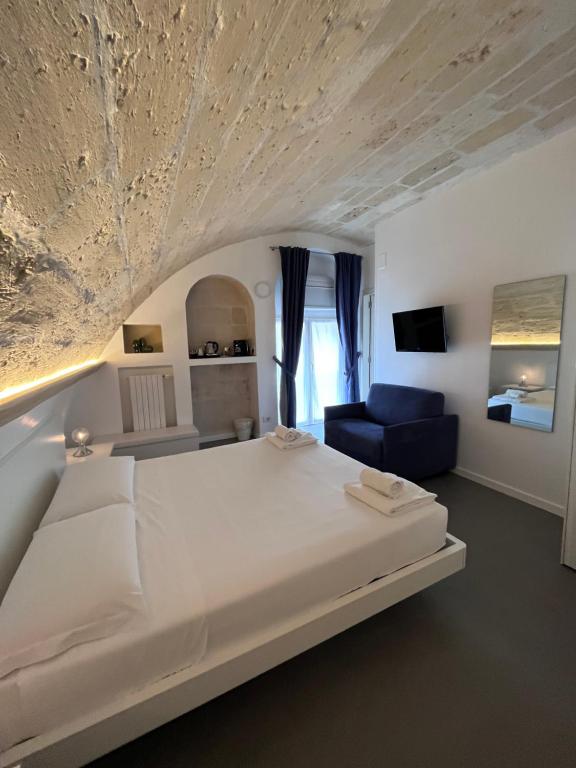 ein Schlafzimmer mit einem großen weißen Bett und einem blauen Sofa in der Unterkunft Il Giramondo Suite&Room in Matera