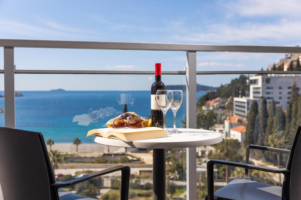 a table with a bottle of wine and a book and a glass at Grand Hotel Park in Dubrovnik