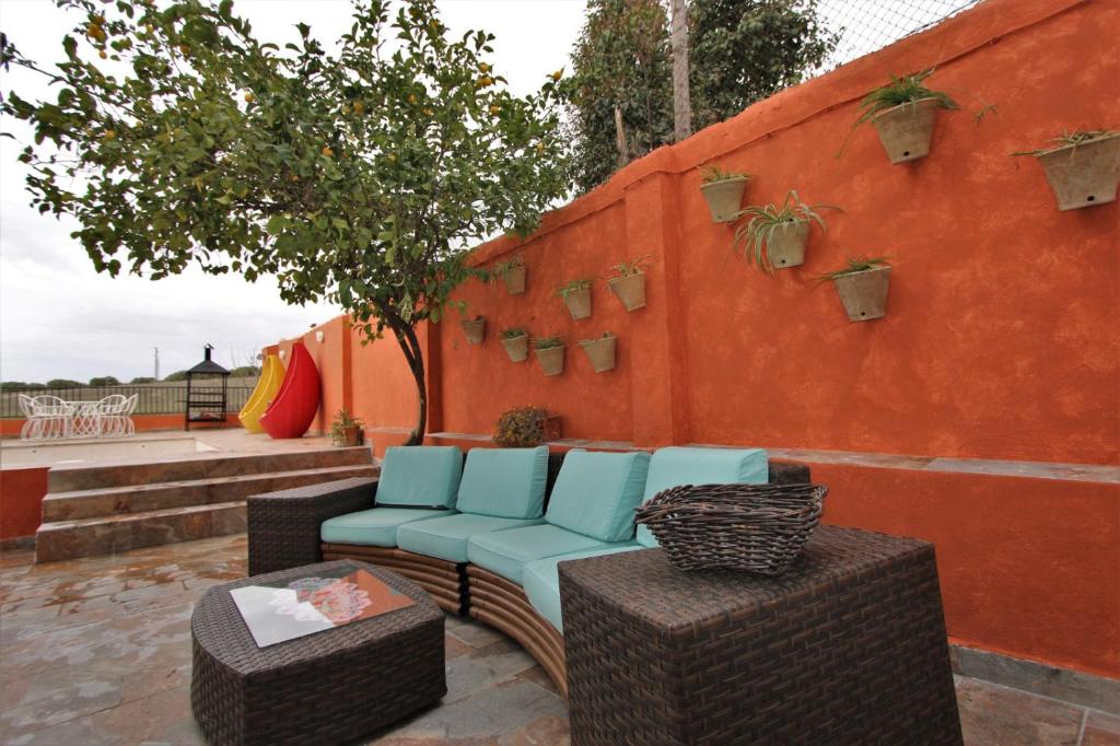 a patio with two chairs and a wall with plants at Casa Rural Mañanas Felices in Martos
