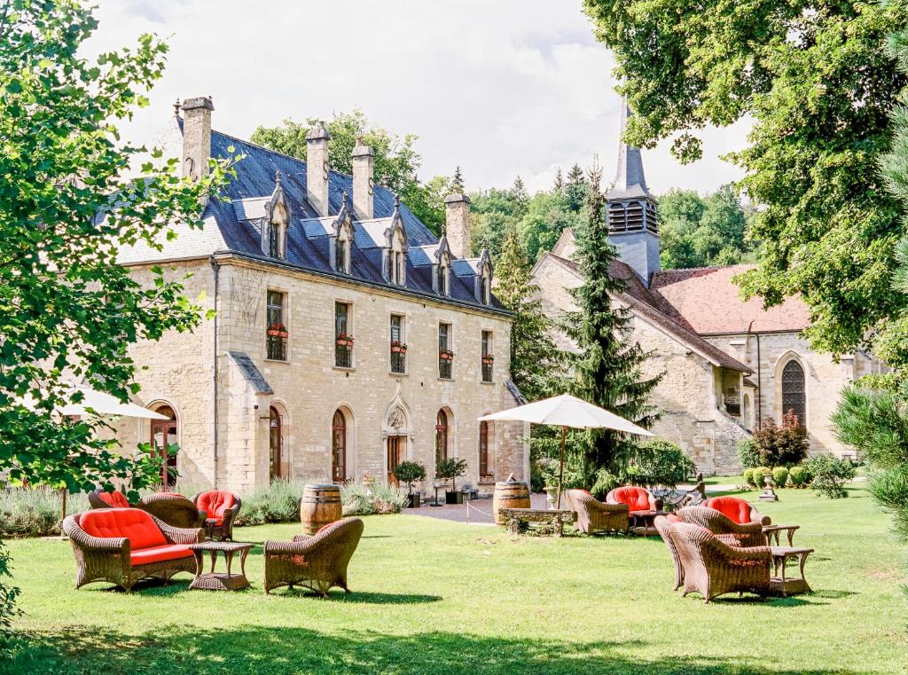 a large stone house with chairs and tables in the yard at Abbaye de la Bussière in La Bussière-sur-Ouche