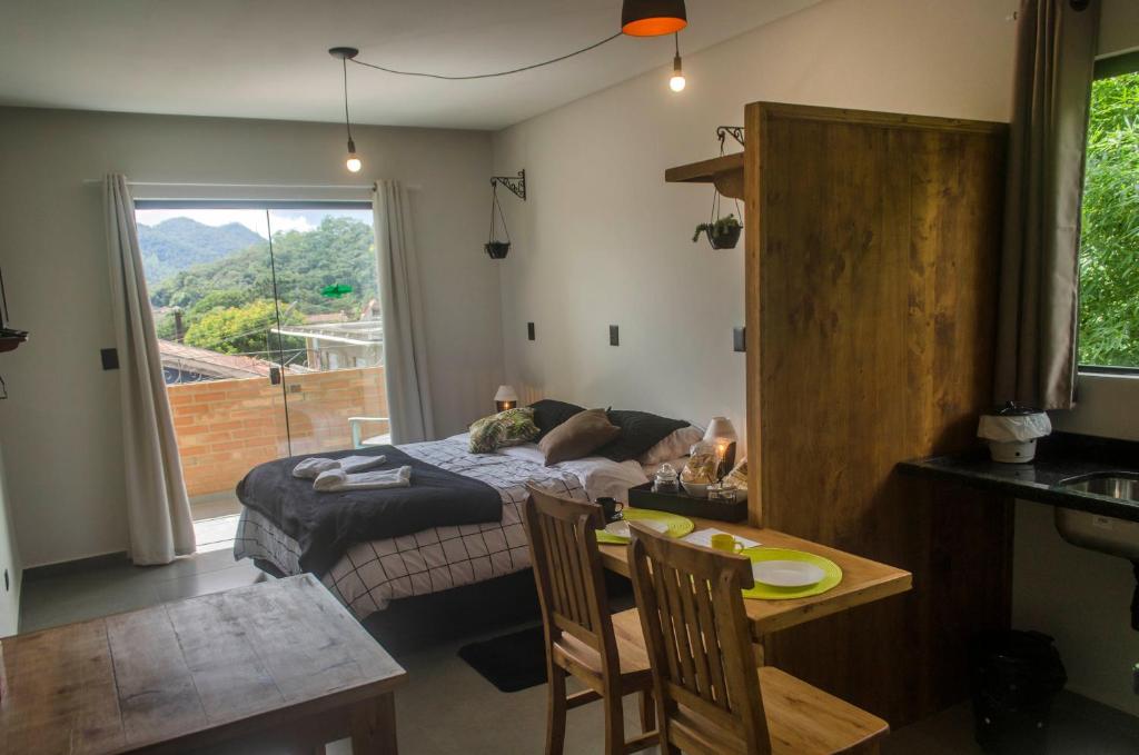 a bedroom with a bed and a table with chairs at Studios Pinhal in Santo Antônio do Pinhal